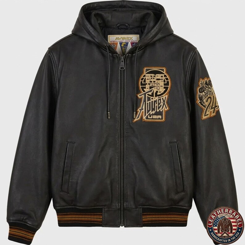 May include: A black leather hooded jacket with a full-length front zipper, ribbed cuffs and hem with brown stripes, and two side pockets. The chest features an embroidered Avirex USA logo patch, and the left sleeve has a circular 24 patch.
