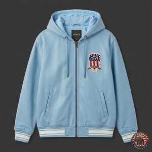 Pu&ograve; includere: Giacca in pelle azzurra con cappuccio e chiusura a zip. La giacca presenta una toppa con la scritta "AVIREX" e un disegno della bandiera americana. I polsini e l'orlo hanno dettagli a righe bianche e blu. Due tasche frontali.