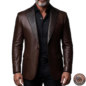 May include: A brown leather blazer with a quilted lapel and a black shirt underneath. The blazer has a two-button closure and two front pockets. The image also shows a black belt and the LeatherRabel logo.