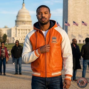 K&ouml;nnte beinhalten: Orange-wei&szlig;e Lederjacke mit Kapuze und Rei&szlig;verschluss. Die Jacke hat einen Brustaufn&auml;her und gestreifte Manschetten. Im Hintergrund sind das US-Kapitol und das Washington Monument zu sehen.
