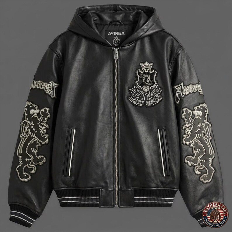 May include: A black leather hooded jacket featuring a full-length front zipper, ribbed cuffs and hem with white stripes, and embroidered patches on the chest and sleeves. The chest patch displays a crown and the text Avirex New York.