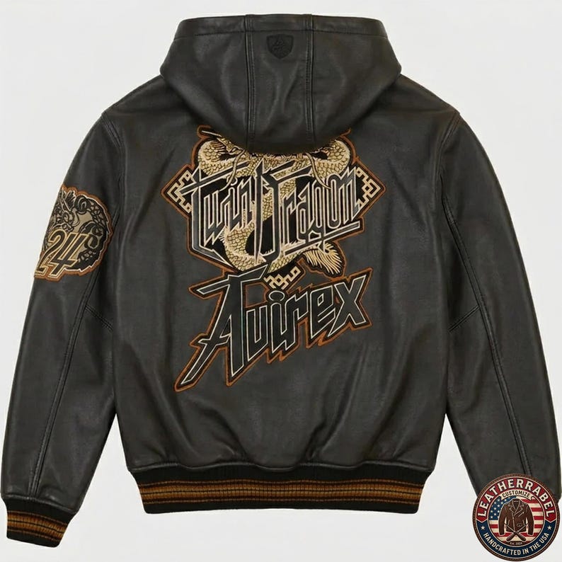May include: A black leather hooded jacket featuring a large embroidered graphic on the back with a golden dragon and the text Twin Dragon Avirex. The left sleeve displays a circular patch with the number 24 and a dragon motif, with ribbed trim.
