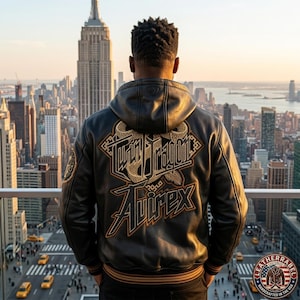 May include: A black leather hooded jacket featuring a large embroidered graphic on the back with the text Twin Dragon and Avirex in gold and brown thread. The jacket has ribbed cuffs and a hem with brown stripes, showcasing detailed stitching.