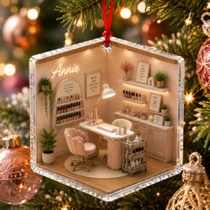 Könnte beinhalten: Ein sechseckiges Acryl-Ornament, das das Innere eines Miniatur-Nagelstudios zeigt, mit einem Schreibtisch, einem rosa Samtstuhl, Regalen voller Nagellackflaschen, einer Lampe und einem Wandschild mit der Aufschrift Annie.