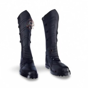 Puede incluir: Un par de botas negras hasta la rodilla con múltiples correas y hebillas. Las botas tienen un diseño texturizado y una suela resistente. Las botas están hechas de un material duradero y son adecuadas para cosplay o disfraces. Aproximadamente 40 cm de alto.