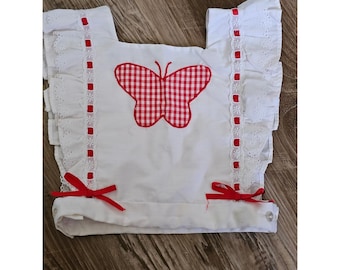 Peto vintage para niña, blanco, con encaje de ojales y mariposas, y lazos de cuadros rojos.