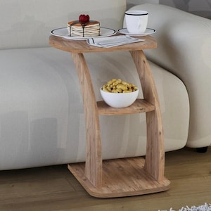 May include: A wooden side table with a distinctive curved design. The top shelf displays a plate with pancakes topped with a red berry, a cup of coffee, and a napkin. The lower shelf holds a white bowl filled with peanuts.