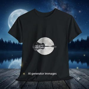Può includere: Una t-shirt nera a maniche corte con una grafica di una luna piena e la sagoma di alberi con il loro riflesso, che creano la forma di una chitarra acustica. Il testo AI generator immages è stampato in bianco nella parte centrale inferiore.