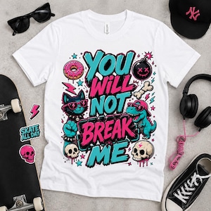Könnte beinhalten: Ein weißes T-Shirt mit einem Grafikdruck, der den Text "YOU WILL NOT BREAK ME" in leuchtendem Pink und Türkis zeigt. Das Design umfasst eine Katze, einen Dinosaurier, einen Donut, eine Bombe und Totenköpfe in einem kräftigen Illustrationsstil.