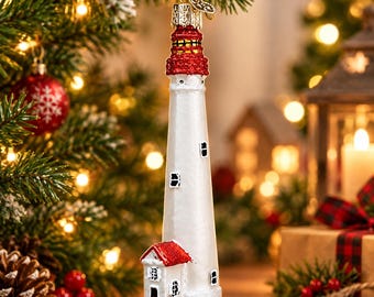 May include: A glass lighthouse ornament featuring a tall white tower with a red glittered top and a small white building with a red roof at the base. The ornament has small black window details and a gold hanging loop at the top for display.