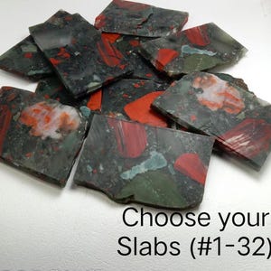 May include: A selection of polished stone slabs in grey, red, and green hues. The slabs display a mottled appearance with diverse patterns and textures. The image includes the text "Choose your Slabs (#1-32)".