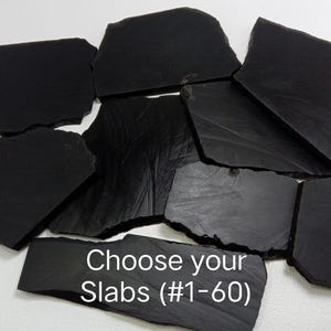 Puede incluir: Una colección de losas de piedra negra de forma irregular. La imagen presenta múltiples piezas con diferentes tamaños y texturas. El texto en la parte inferior dice "Choose your Slabs (#1-60)".