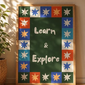 May include: A framed art print with a green background and the words "Learn & Explore" in white. The border features colorful squares with star designs in various colors, including blue, orange, and white. The frame is made of light-colored wood.