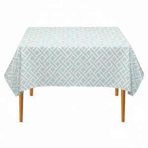 May include: A square tablecloth featuring a light blue and white geometric lattice pattern. The fabric drapes over a table with four light brown wooden legs, displaying a repeating woven-style design across the entire surface area.