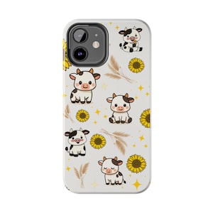 May include: A white phone case featuring a repeating pattern of cartoon cows, sunflowers, and wheat stalks. The cows are black and white with smiling faces. Yellow sunflowers and gold stars are scattered across the case.