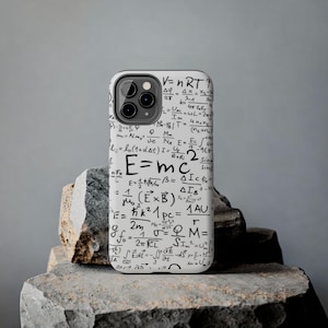 Puede incluir: Una funda de smartphone blanca con un denso estampado negro de varias ecuaciones físicas y matemáticas, incluyendo E=mc2 y V=nRT. La funda tiene una forma rectangular con esquinas redondeadas y un recorte para un sistema de triple cámara.