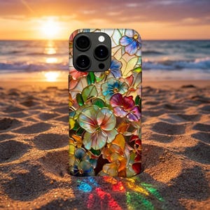 Pode incluir: Uma capa de telefone colorida com um design floral em vitral. A capa apresenta flores em tons de vermelho, azul, verde e amarelo, com contornos dourados. O fundo é uma cena de praia com um pôr do sol.