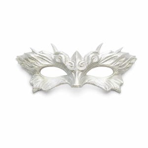 Puede incluir: Una máscara de carnaval de color plateado con patrones intrincados y fluidos en forma de hoja y protuberancias afiladas a lo largo del borde superior. La máscara tiene dos aberturas ovaladas para los ojos y un acabado metálico liso.