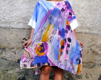 May include: A woman wearing a blue, pink, and white abstract print dress with white sunglasses. The dress has a loose, flowing fit and is knee-length.