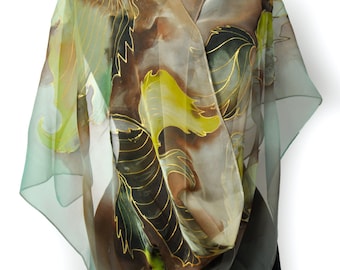 May include: A green, brown, and gold silk scarf with a floral pattern. The scarf is draped over a black mannequin.