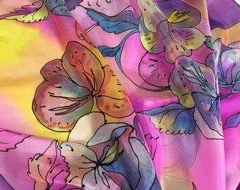 Könnte beinhalten: Ein lebendiger Seidenschal mit floralem Design in Rosa, Lila, Gelb und Blau. Die handgemalten Blumen haben schwarze Umrisse, die einen starken Kontrast bilden. Der Schal ist drapiert und zeigt seinen fließenden Stoff.