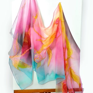 May include: A pink, yellow, and blue silk scarf with a floral design. The scarf is draped over an easel.