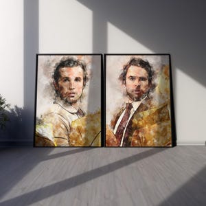 May include: Two framed wall art prints featuring watercolor-style portraits of two men. The left print shows a man in a light shirt, while the right print depicts a man in a suit and tie. Both portraits use warm yellow and brown tones.