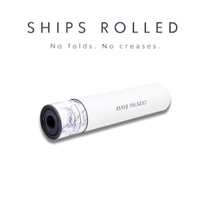 May include: A rolled mat featuring a white exterior with the text MAHJ PALAZZO in dark lettering. The inner layer displays a blue and white floral pattern. Above the mat, the text reads SHIPS ROLLED No folds. No creases.