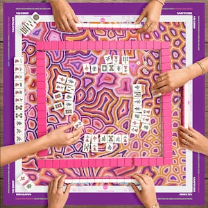 Può includere: Un set di Mahjong con un tabellone rosa e viola con un motivo a forma di agata. Il set include rastrelliere rosa per le tessere, dadi e tessere con caratteri cinesi. Sono visibili diverse mani, a indicare una partita in corso. Le dimensioni del tabellone sono in centimetri.