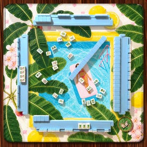May include: A square mahjong mat featuring a swimming pool scene with a person on a pink float, surrounded by green banana leaves, lemons, and pink flowers. Four light blue tile racks are positioned at the edges, with scattered mahjong tiles.