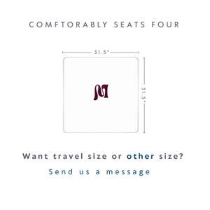 K&ouml;nnte beinhalten: Ein quadratischer wei&szlig;er Tisch mit einem dunkelroten Buchstaben M in der Mitte. Der Tisch misst 80 cm mal 80 cm. Der Text dar&uuml;ber lautet COMFTORABLY SEATS FOUR. Der Text darunter lautet Want travel size or other size? Send us a message.