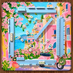 Könnte beinhalten: Ein Mahjong-Set mit einer Spielmatte, die eine mediterrane Küstenstadt, rosa Gebäude, einen rosa Roller und blühende Blumen zeigt. Das Set enthält vier hellblaue Ablageleisten und weiße Spielsteine mit grünen Symbolen.