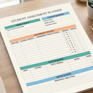 May include: A student assignment planner with sections for weekly goals, assignment tracking, tests, and notes. The planner has a cream-colored background with teal, orange, and blue accents. A gold pen and small potted plant are on the wooden desk.