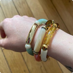 Elastische armband van acryl kralenbuisjes met decoratieve elementen tussen de buisjes (kralen, kleine buisjes).