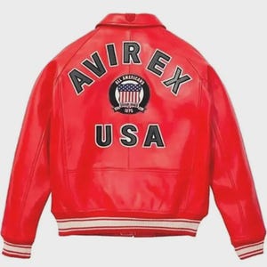 Pu&ograve; includere: Giacca in pelle rossa con la scritta "AVIREX" in lettere bianche sulle spalle. La giacca presenta una toppa circolare con le scritte "ALL AMERICANS" e "ESTABLISHED 1975". La parola "USA" &egrave; stampata in lettere bianche.
