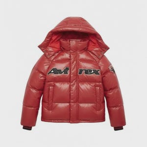 Pode incluir: Casaco acolchoado vermelho com capuz. O casaco apresenta o texto "Avi Rex" em preto e branco no peito. O casaco tem um acabamento brilhante e um design acolchoado.