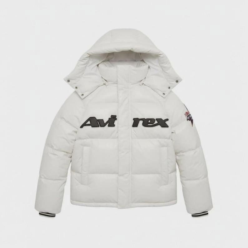 Pode incluir: Casaco acolchoado branco com capuz e o nome da marca "Avi rex" em letras pretas no peito. O casaco tem fecho de correr e um pequeno emblema na manga superior. Os punhos t&ecirc;m riscas brancas e pretas.
