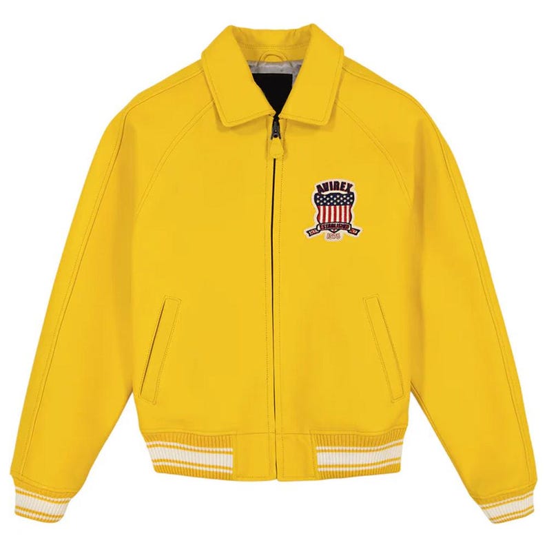 Pu&ograve; includere: Giacca giallo brillante con zip, colletto e polsini e orlo a coste. La giacca presenta una toppa sul petto con un disegno a scudo e la scritta "AVIREX ESTABLISHED 1975". I polsini e l'orlo hanno strisce bianche.