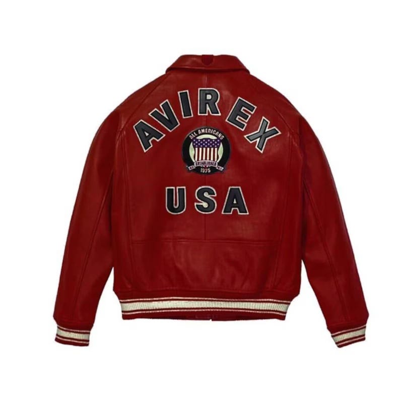 May include: Red leather jacket with white and navy blue striped cuffs and hem. The back features the word "AVIREX" above a circular emblem and the word "USA". The emblem includes the text "ALL AMERICANS ESTABLISHED 1975".