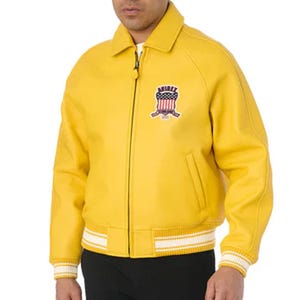 Pu&ograve; includere: Giacca in pelle giallo brillante con chiusura a zip, colletto e orlo e polsini a righe bianche e gialle. La giacca presenta una toppa sul petto con un design a stemma.