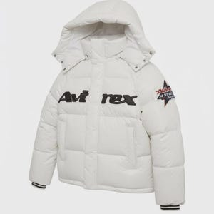 Pode incluir: Um casaco acolchoado branco com capuz. O casaco apresenta o texto "Avi rex" em preto no peito e um patch na manga. Os punhos t&ecirc;m riscas brancas e pretas.
