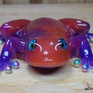 Rana roja y morada con dedos de cuentas de perlas.