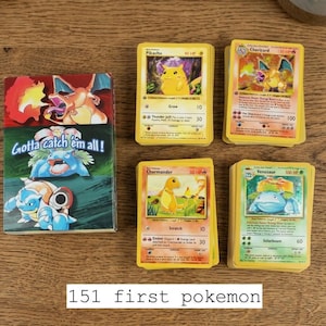 May include: A collection of Pokemon trading cards, including Charizard, Pikachu, Charmander, and Venusaur. The cards are yellow with colorful illustrations of the characters. A card holder with the text "Gotta catch 'em all!" is also present. The text "151 first pokemon" is at the bottom.
