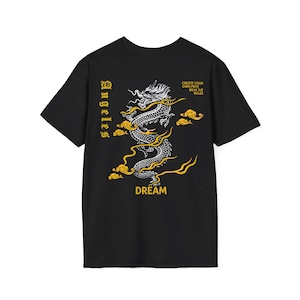 Può includere: T-shirt nera con un disegno di drago bianco e oro. Il drago è circondato da nuvole e la parola "DREAM" è stampata sotto. La parola "Los Angeles" è stampata verticalmente a sinistra e la frase "CREATE YOUR OWN PATH, BREAK THE RULES" è in alto a destra.