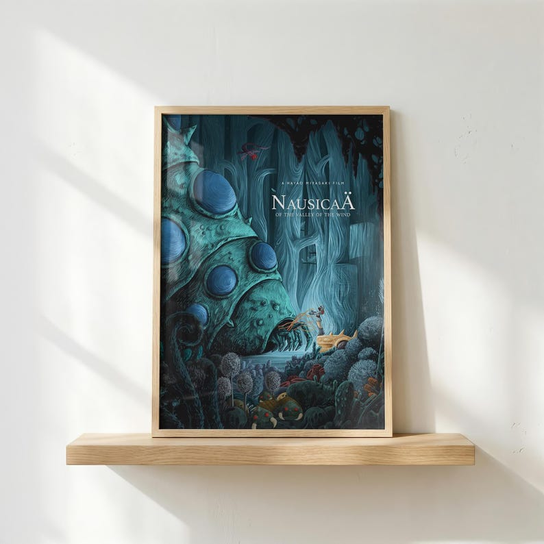 K&ouml;nnte beinhalten: Gerahmtes Poster mit dem Titel "Nausica&auml; aus dem Tal der Winde". Das Kunstwerk zeigt eine fantastische Szene mit einer gro&szlig;en, teal-farbenen Kreatur und einem kleinen Fahrzeug in einer Waldkulisse. Das Poster wird auf einem Holzregal pr&auml;sentiert.