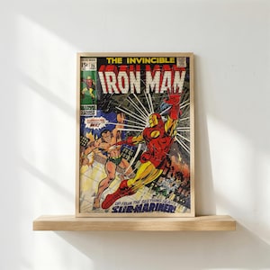 May include: A framed vintage comic book cover featuring Iron Man in a red and gold suit, battling Sub-Mariner. The cover art is vibrant with action lines and the text "The Invincible Iron Man" and "Sub-Mariner". The comic is displayed on a wooden shelf.