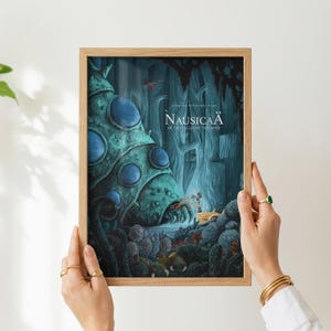 K&ouml;nnte beinhalten: Gerahmtes Poster mit Kunst aus dem Film "Nausica&auml; aus dem Tal der Winde". Das Poster zeigt eine detaillierte Illustration in T&uuml;rkis- und Blaut&ouml;nen, die eine fantastische Landschaft und Charaktere darstellt. Der Rahmen ist aus hellem Holz.
