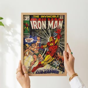 May include: A framed vintage comic book cover featuring Iron Man in a red and gold suit, with the text "The Invincible Iron Man." The artwork includes other characters and the words "Sub-Mariner."