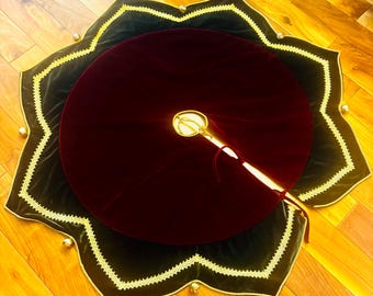 May include: A circular tree skirt featuring a deep burgundy velvet center and a dark green velvet outer border with a scalloped edge. The border is trimmed with gold lace and small gold bells at each point, with a central opening and ties.