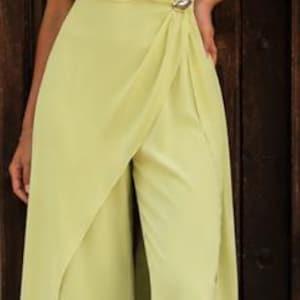May include: A lime green jumpsuit featuring an off-the-shoulder neckline with draped fabric across the bodice. The garment includes a side waist accent with a metallic detail and wide-leg trousers with an integrated wrap-style skirt overlay.